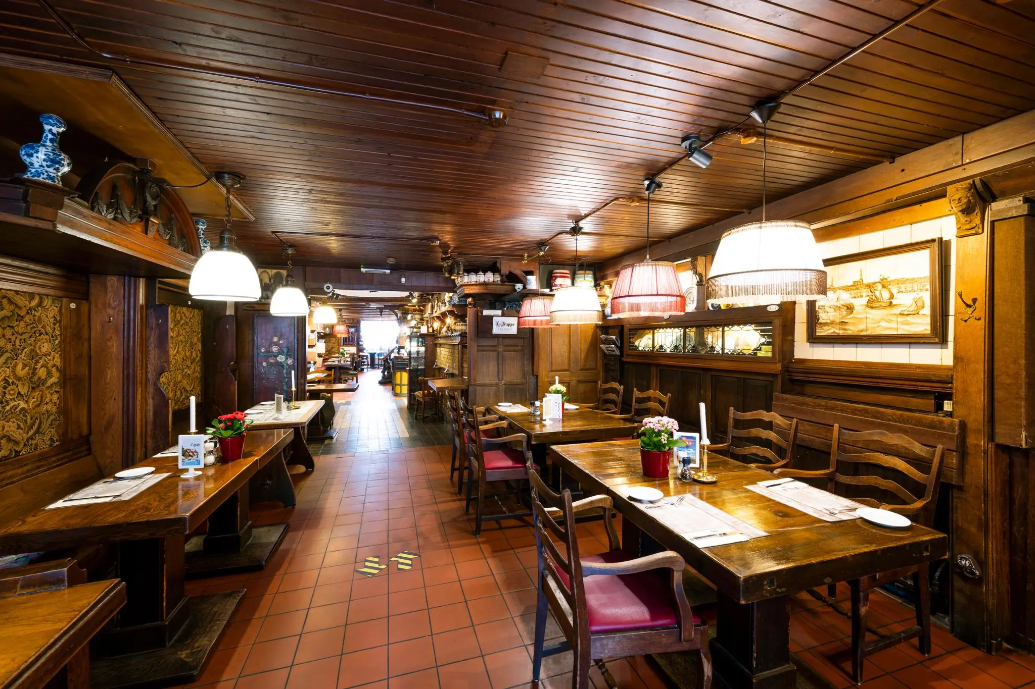 Gezellige eetruimte met houten interieur en gedekte tafels in een traditioneel Amsterdams restaurant aan de Nieuwezijds Voorburgwal.